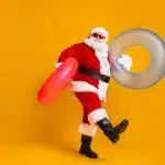 Full size profile side photo of white grey hair bearded santa claus rest x-mas christmas time go hold rubber circle wear sunglass headwear boots isolated bright shine color background